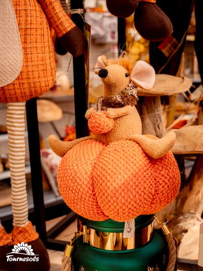 Décoration automnale avec une souris en peluche sur une citrouille textile.